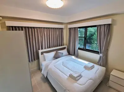 a bedroom with a large white bed with a window at Kata beach townhouse in Kata Beach