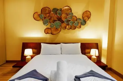 a bedroom with a bed with two lamps and areath of cactus at Blue Moon by G Estate Phuket in Ban Saiyuan (1)