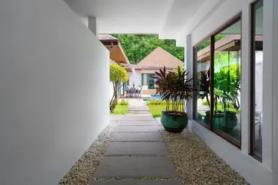 a hallway leading to a house with a plant at Blue Moon by G Estate Phuket in Ban Saiyuan (1)