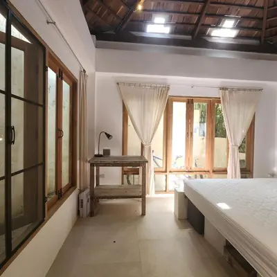 a bedroom with a bed and a table and windows at The Hip House Villa Phuket in Ban Bang Khu