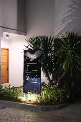 a sign in front of a building with palm trees at Alisse Stay Phuket Layan in Phuket Town