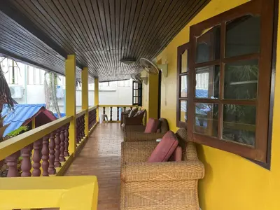 a balcony with chairs and a table and a yellow wall at Baan Orchid Guesthouse in Patong Beach