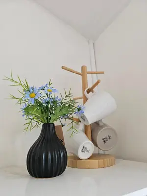 a vase with flowers in it next to two hair dryers at Haru Inn Airport in Ban Bo Han