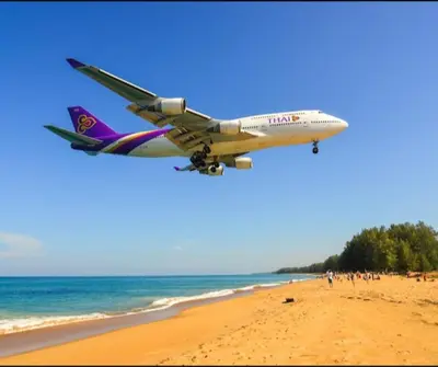 an airplane flying over a beach with people on it at Haru Inn Airport in Ban Bo Han