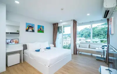 a white bedroom with a large white bed and a couch at Ozone Phuket Kata Beach Resort & Wellness in Kata Beach