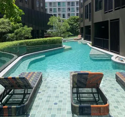 a swimming pool with two chairs in a building at PRIME TOWN Phuket Resort & Wellness in Ban Rangeng