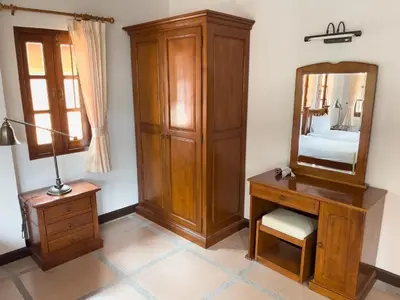a bedroom with a wooden dresser and a mirror at Ongsantiphap villa resort in Ban Klang