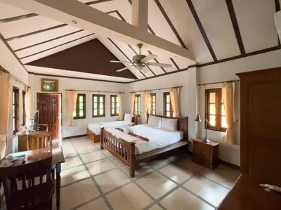 a bedroom with a bed and a desk and windows at Ongsantiphap villa resort in Ban Klang
