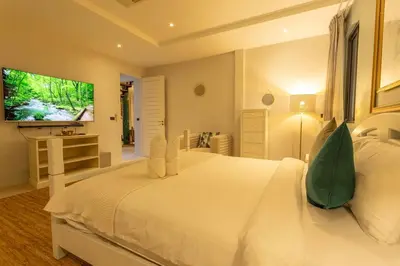 a white bedroom with a large white bed and a television at Brand new, designer furnishing, hot tub, gym, pool V98 in Rawai Beach