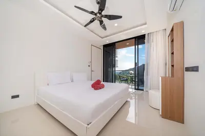 a bedroom with a white bed and a ceiling fan at Sea & Mountain Views Apartment at VV Patong A603 in Patong Beach