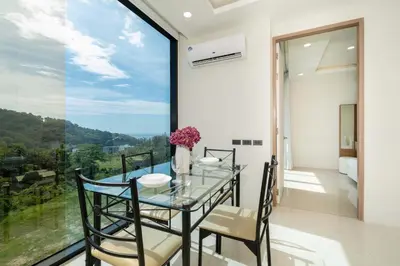 a dining room with a glass table and chairs and a large window at Sea & Mountain Views Apartment at VV Patong A603 in Patong Beach