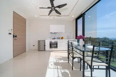 a kitchen with a dining table and a ceiling fan at Sea & Mountain Views Apartment at VV Patong A603 in Patong Beach