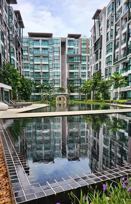 an apartment complex with a reflecting pool in front of buildings at Stylish Apartment with Workspace 10 Minutes from the Beach for min 30 Day Stays in Phuket Town