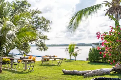 a picnic table on the lawn next to the water at Mai Khao Beach Luxury 7-bedroom villa 0 meters from the sea double infinity pool maid, outdoor wedding sea fishing in Mai Khao Beach