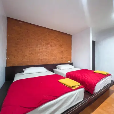 two beds in a bedroom with red sheets and yellow blankets at Happy House in Phi Phi Don