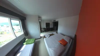 a bedroom with a bed with an orange pillow and a window at Chollada Inn in Kamala Beach