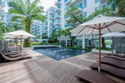 a swimming pool with chairs and umbrellas in a building at Fishermens Harbour Urban Resort - SHA Extra Plus in Patong Beach