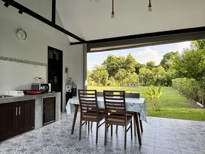 a kitchen with a table and chairs and a large window at Moonlight Cottage in Ban Pa Khlok