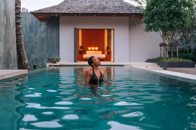 a woman standing in the water in a swimming pool at Allure Villa in Bangtao in Ban Pak Lak