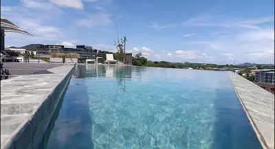 a large swimming pool with blue water on a building at The Proud Rawai Studio in Phuket Town