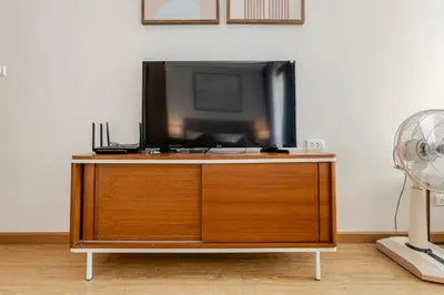 a tv sitting on top of a wooden cabinet at The Proud Rawai Studio in Phuket Town