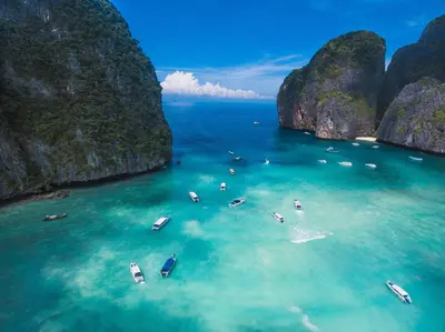 a group of boats in the water in a bay with limestone cliffs at Lucky Dorm in Phi Phi Don