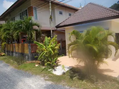 a house with palm trees in front of a street at Absolute calm for long sleepers and others in Kamala Beach