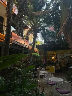 a patio with tables and chairs and palm trees at Nai Harn Beach Condo (C2) in Rawai Beach