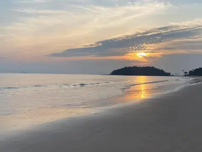 a beach with the sun setting in the distance at Green Tree Cottage 4 in Klong Muang Beach