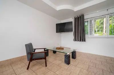 a room with a chair and a table and a tv at Villa Olympus Ocean Vista Kata Beach in Kata Beach