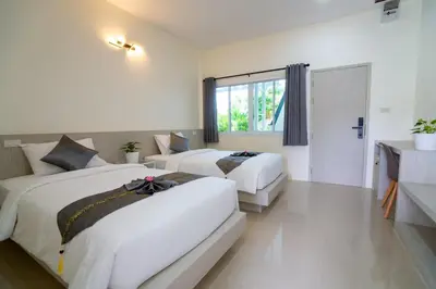 a hotel room with two beds and a window at Puean Chang Resort Phuket in Thalang
