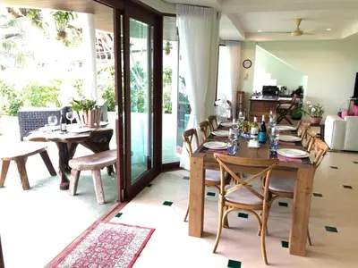 a dining room with a long wooden table and chairs at Bali style 4 bedroom beachfront Villa Ao Yon in Ban Ao Makham