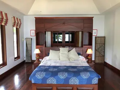 a bedroom with a large bed with a wooden headboard at Bali style 4 bedroom beachfront Villa Ao Yon in Ban Ao Makham
