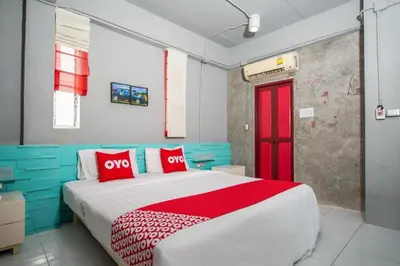 a bedroom with a large bed with red and blue at OYO 292 The Oddy Hip Hotel in Patong Beach
