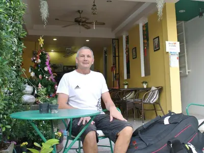 a man sitting at a table in a room at Machima House in Phuket Town