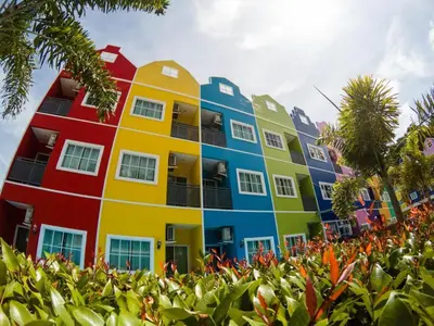 a row of colorful buildings with the sun in the background at Holland Resort Phuket in Ban Phlu Yai