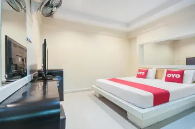 a bedroom with a bed with red pillows and a television at OYO 1172 Goodnight Resort in Phuket Town