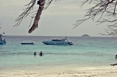 two people in the ocean with a boat in the water at Ocean and Ole Patong in Patong Beach