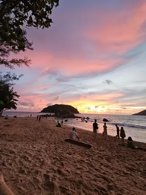 a group of people on a beach at sunset at Lakshmi beach house in Phuket Town