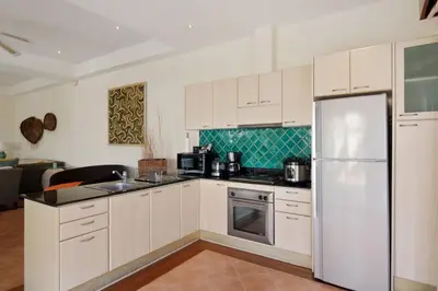 a kitchen with white cabinets and a refrigerator at Laguna Fairway View Villa in Bang Tao Beach