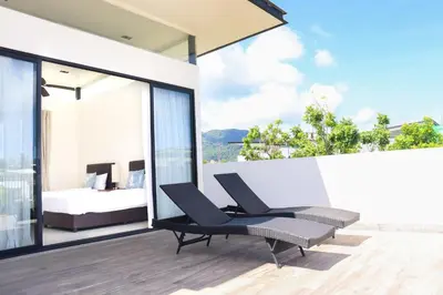 a bedroom with a bed and a chair on a balcony at Super Friendly TH Laguna Park in Phuket Town