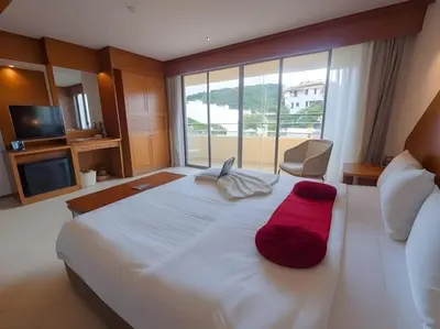 a bedroom with a large white bed with a red pillow at Hack Patong Beach Hotel in Patong Beach