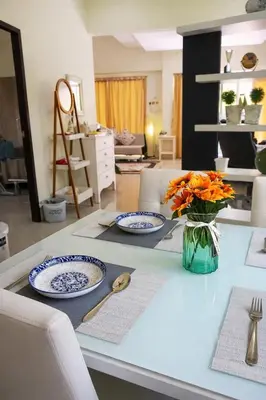 a table with two plates and a vase of flowers on it at Grand Chalong Family House in Chalong