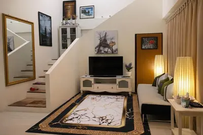 a living room with a tv and a staircase at Grand Chalong Family House in Chalong