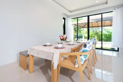 a dining room with a white table and chairs at Garden pool villa V110 in Kata Beach