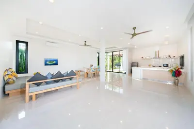 a white living room with couches and a kitchen at Garden pool villa V110 in Kata Beach