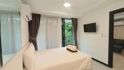a hotel room with a bed and a window at Rawai Beach Condo by Holy Cow in Nai Harn Beach