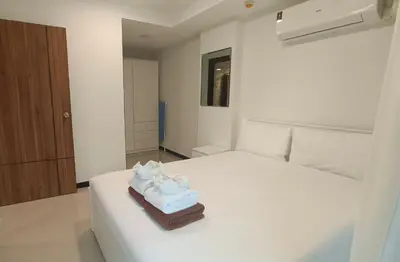 a bedroom with a white bed with towels on it at Rawai Beach Condo by Holy Cow in Nai Harn Beach