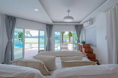 a bedroom with three beds and a balcony at Coco Golf Villa in Ban Huai Luk (1)