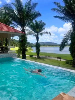 a man in a swimming pool with a view of the water at Coco Golf Villa in Ban Huai Luk (1)